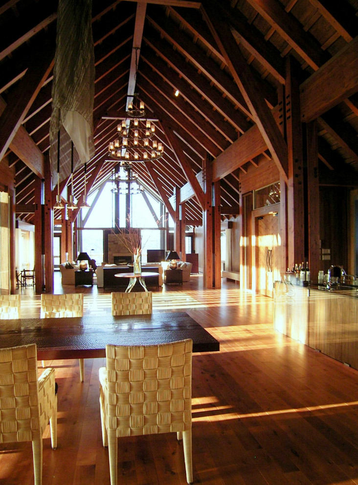 На фото: большая гостиная-столовая в классическом стиле с коричневыми стенами, полом из фанеры, стандартным камином, фасадом камина из камня и коричневым полом