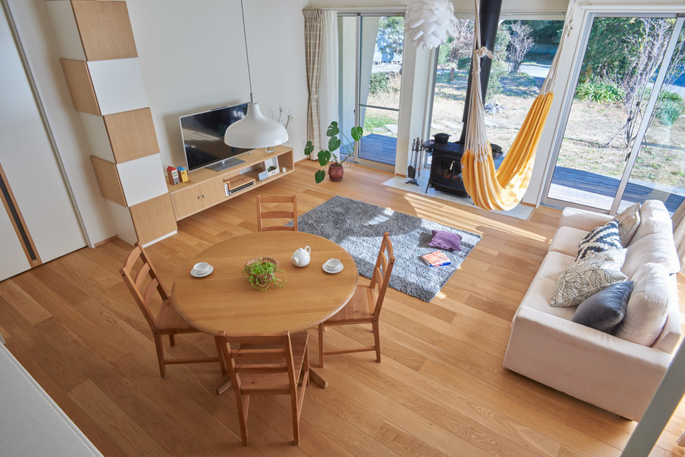 Immagine di una sala da pranzo aperta verso il soggiorno country con pareti bianche, pavimento in legno massello medio e stufa a legna