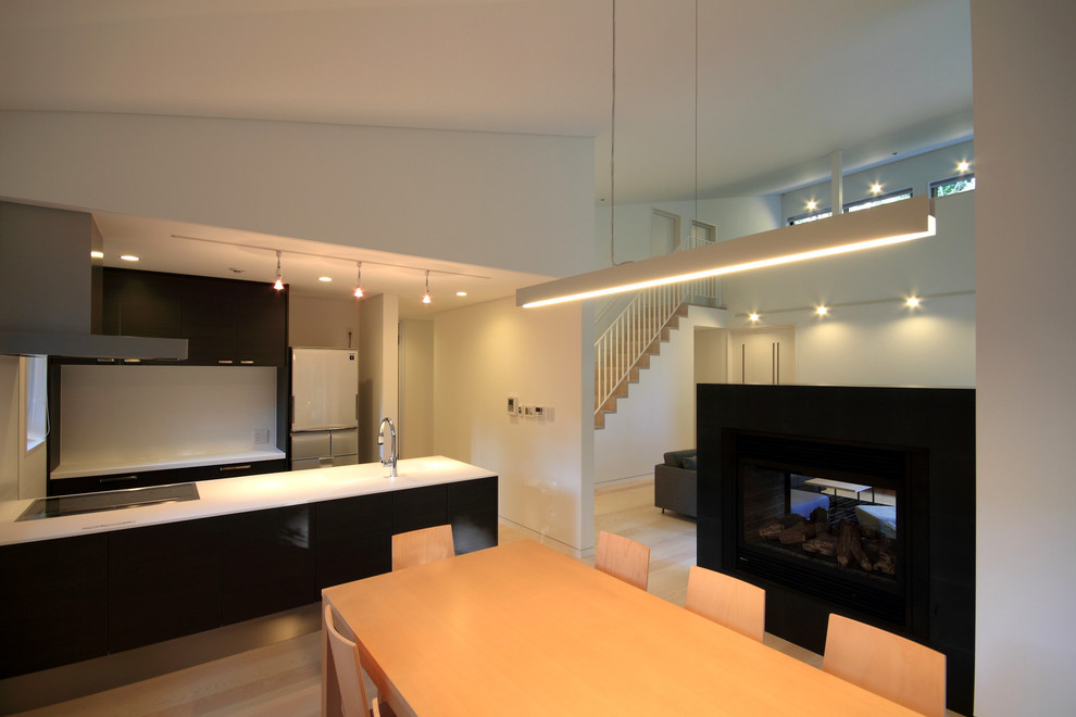Идея дизайна: кухня-столовая среднего размера в стиле модернизм с белыми стенами, полом из фанеры, двусторонним камином, фасадом камина из камня и бежевым полом