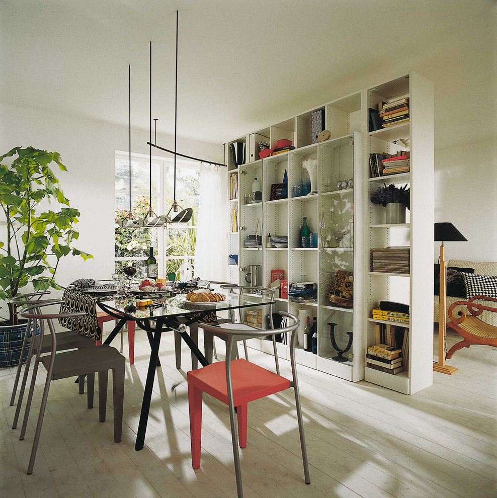 На фото: столовая в современном стиле с белыми стенами и деревянным полом без камина