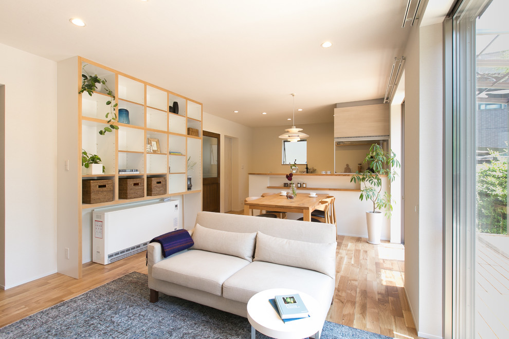 Diseño de comedor contemporáneo abierto con paredes blancas, suelo de madera clara y suelo beige