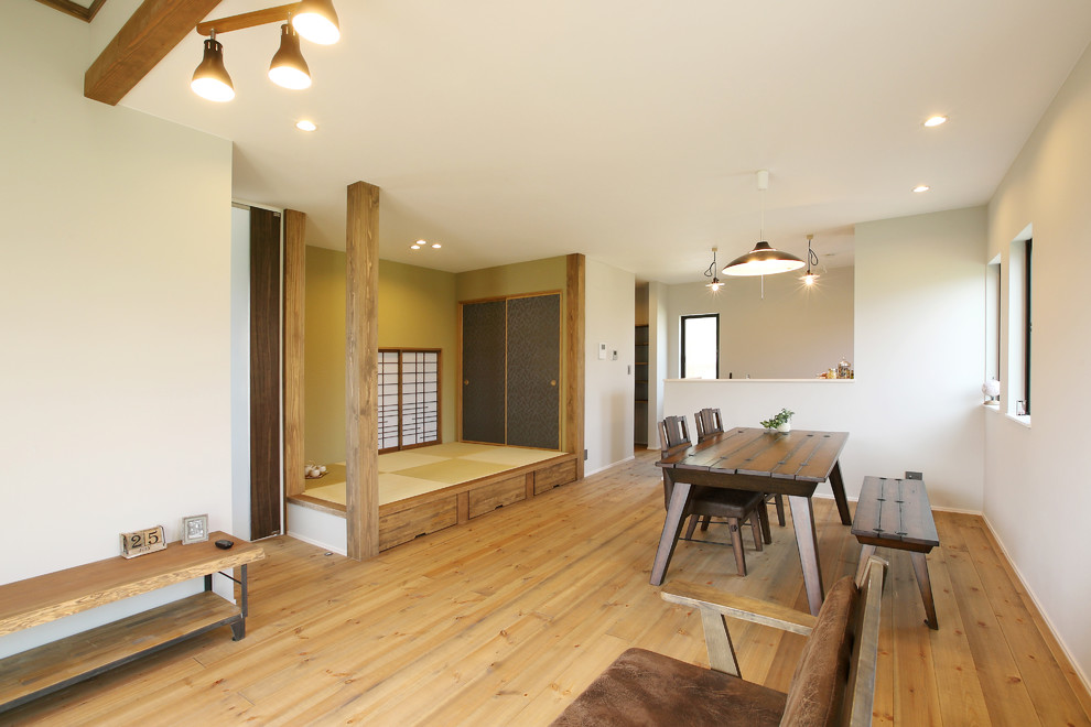 Réalisation d'une salle à manger asiatique avec un mur blanc, un sol en bois brun et un sol marron.
