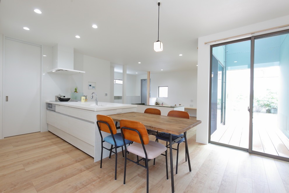 Ispirazione per una sala da pranzo aperta verso il soggiorno moderna con pareti bianche, parquet chiaro e pavimento beige