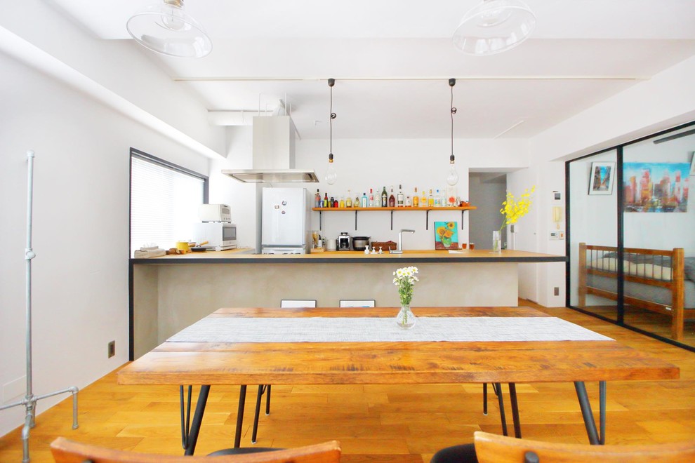 Esempio di una sala da pranzo aperta verso il soggiorno industriale con pareti bianche, pavimento in legno massello medio e pavimento marrone