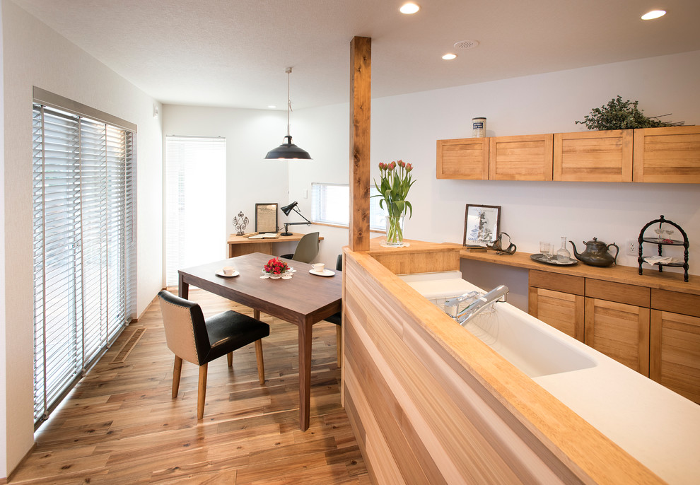 Immagine di una piccola sala da pranzo aperta verso il soggiorno etnica con pareti bianche, pavimento in legno massello medio e pavimento marrone
