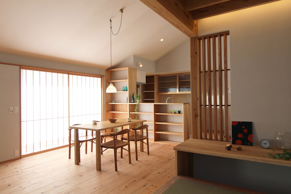 Imagen de comedor minimalista de tamaño medio abierto con paredes blancas, suelo de madera en tonos medios y suelo marrón
