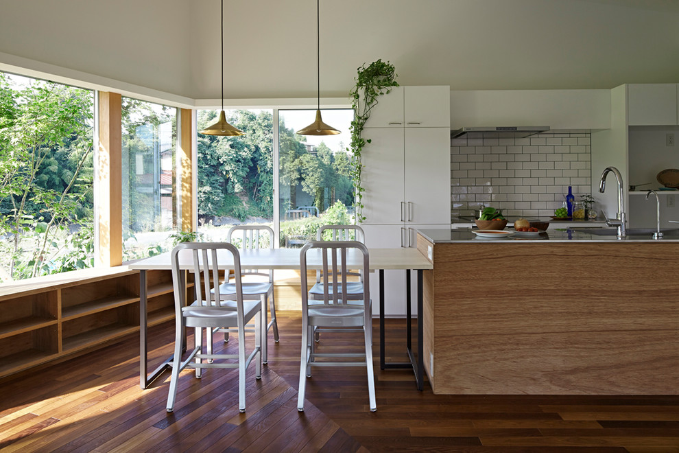 Foto de comedor actual abierto con paredes blancas, suelo de madera en tonos medios y suelo marrón