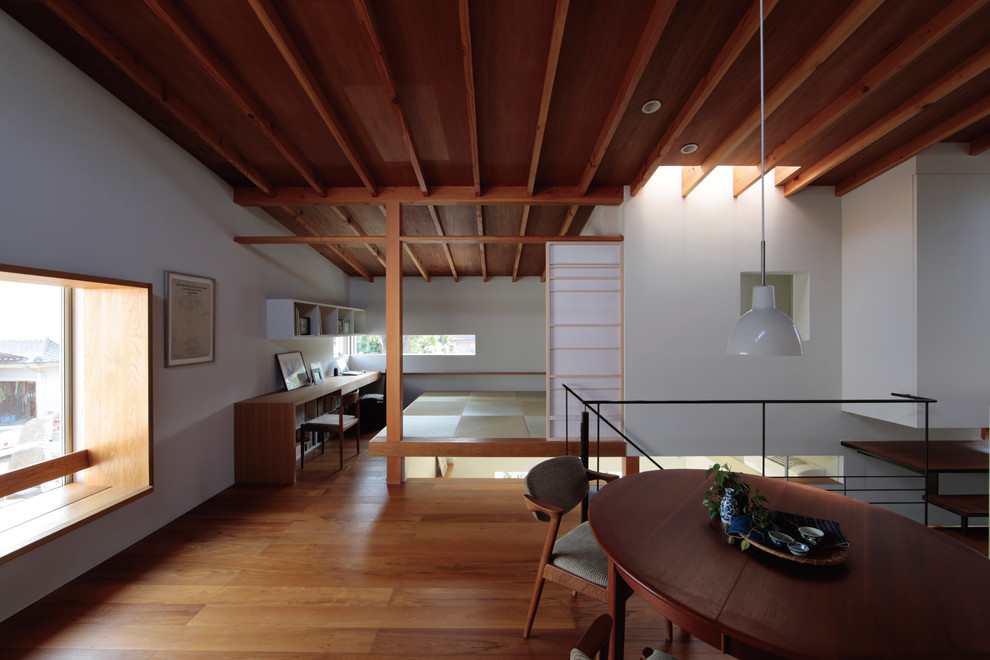 Idée de décoration pour une salle à manger ouverte sur le salon asiatique avec un mur blanc, un sol en bois brun et un sol marron.