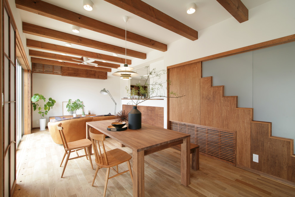 Esempio di una sala da pranzo aperta verso il soggiorno etnica con pareti bianche, parquet chiaro e pavimento beige