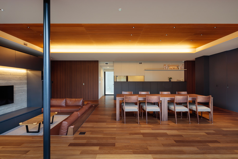 Inspiration pour une salle à manger ouverte sur le salon design avec un mur multicolore, un sol en bois brun et un sol marron.