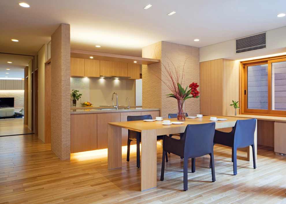Foto di una sala da pranzo aperta verso la cucina contemporanea con parquet chiaro e pavimento beige