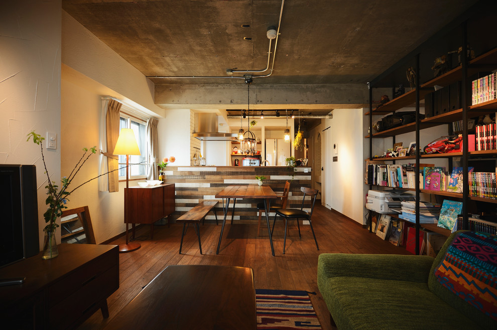 Immagine di una sala da pranzo aperta verso il soggiorno industriale con pareti bianche, parquet scuro e pavimento marrone