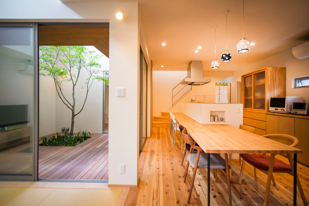 Foto di una sala da pranzo aperta verso il soggiorno etnica di medie dimensioni con pavimento in legno massello medio, pavimento marrone e pareti bianche