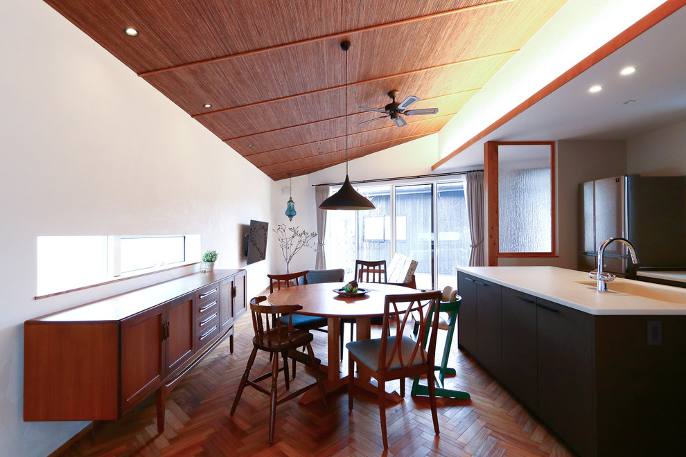 Exempel på en mellanstor asiatisk matplats med öppen planlösning, med vita väggar, mellanmörkt trägolv och brunt golv