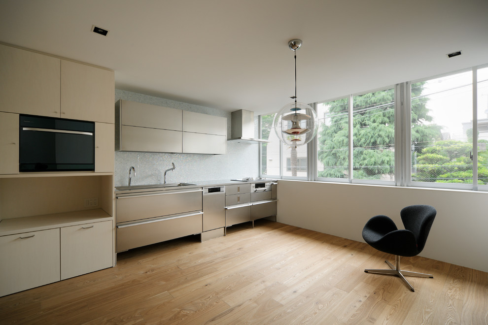 Idee per una grande sala da pranzo aperta verso la cucina minimalista con pareti bianche, pavimento in legno massello medio e pavimento marrone