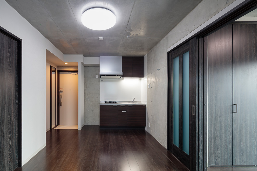 Inspiration pour une salle à manger ouverte sur la cuisine minimaliste de taille moyenne avec un mur gris, un sol en contreplaqué et un sol noir.