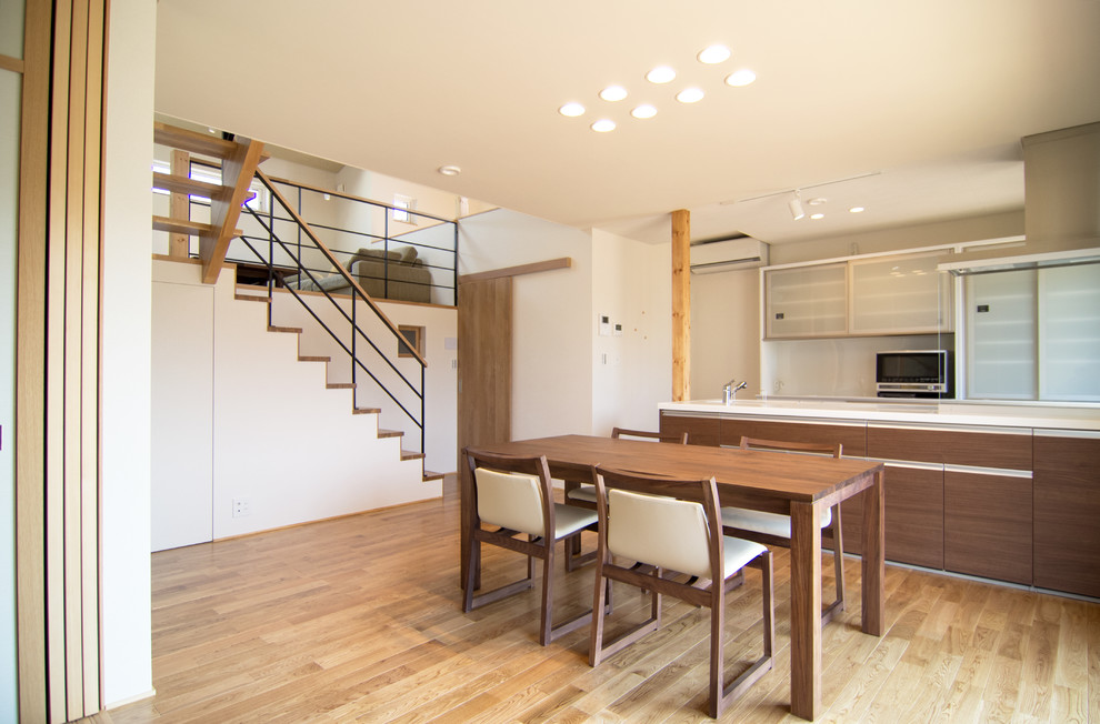 Immagine di una sala da pranzo aperta verso il soggiorno country con pareti bianche, pavimento in legno massello medio e pavimento marrone