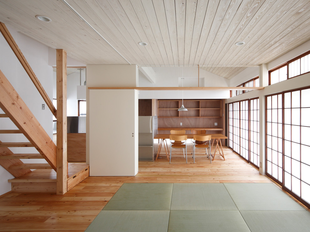 Idées déco pour une salle à manger ouverte sur le salon asiatique avec un mur blanc, un sol en bois brun et un sol marron.