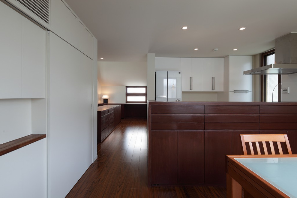 Foto på ett litet kök med matplats, med vita väggar, plywoodgolv, en dubbelsidig öppen spis och brunt golv