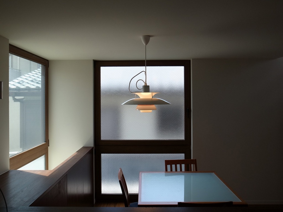Inspiration pour une petite salle à manger ouverte sur la cuisine avec un mur blanc, un sol en contreplaqué, une cheminée double-face et un sol marron.