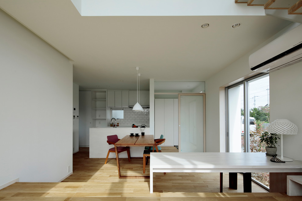 На фото: гостиная-столовая в современном стиле с белыми стенами, светлым паркетным полом и бежевым полом с