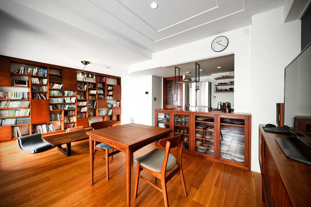 Midcentury open plan dining room with white walls, medium hardwood flooring and brown floors.