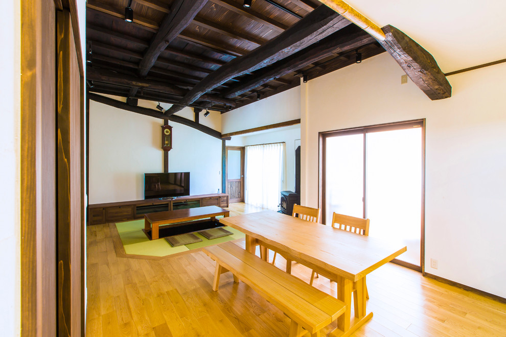 Inspiration pour une salle à manger ouverte sur le salon asiatique avec un mur blanc, un sol en bois brun, un poêle à bois et un sol marron.