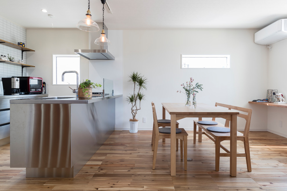 Immagine di una sala da pranzo nordica con pareti bianche, pavimento in legno massello medio e pavimento marrone