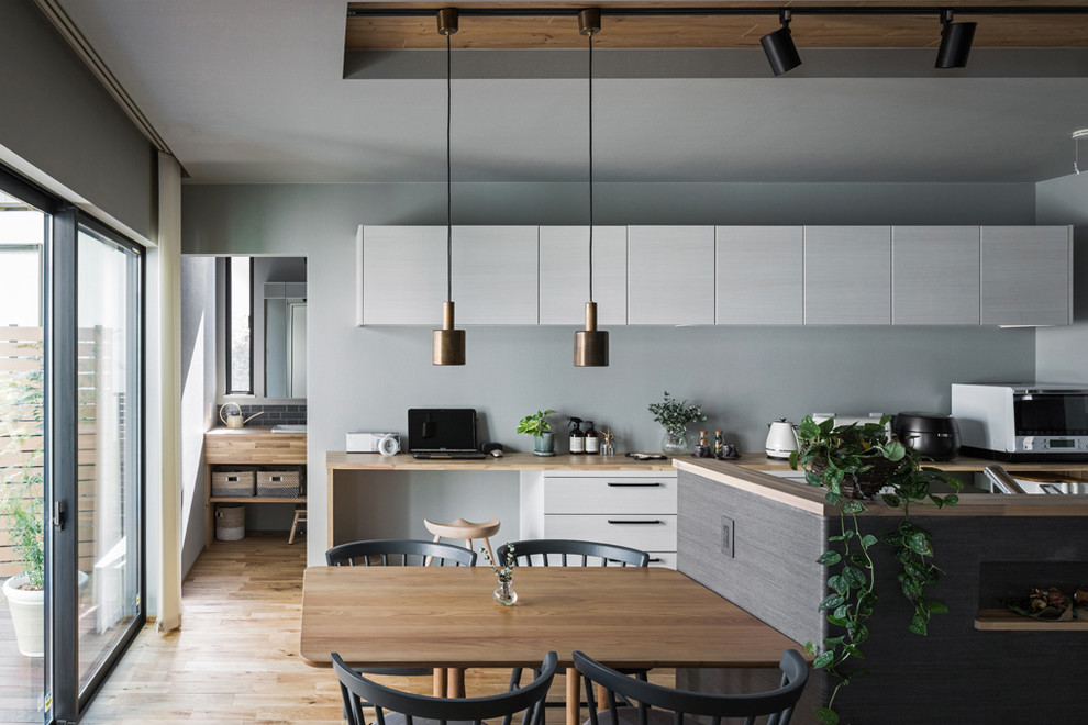 Aménagement d'une salle à manger ouverte sur le salon scandinave de taille moyenne avec un mur gris, un sol en bois brun et un sol marron.