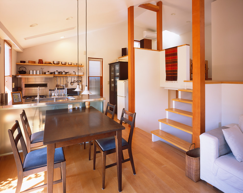 Bild på en liten funkis matplats med öppen planlösning, med vita väggar, mellanmörkt trägolv och brunt golv