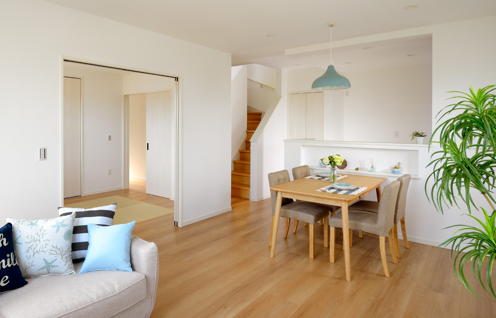 Immagine di una sala da pranzo aperta verso il soggiorno scandinava con pareti bianche, pavimento in compensato e pavimento beige