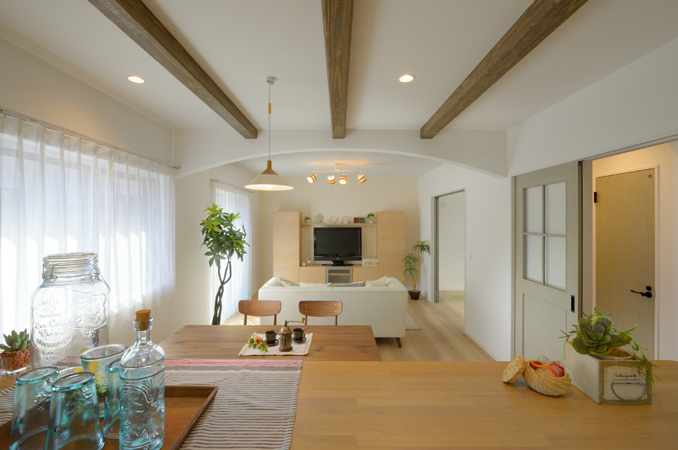 Immagine di una sala da pranzo aperta verso il soggiorno moderna con pareti bianche, pavimento in compensato e pavimento beige