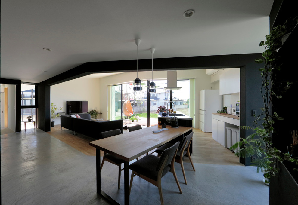 Exemple d'une salle à manger ouverte sur le salon moderne avec un mur noir, sol en béton ciré et un sol gris.