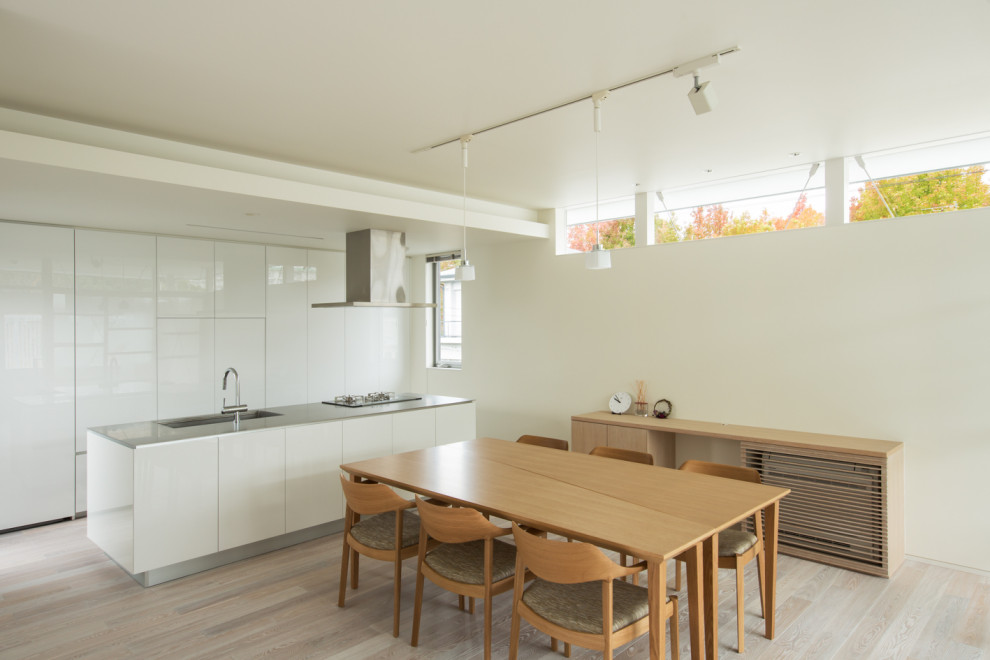 Esempio di una sala da pranzo aperta verso la cucina moderna con pareti bianche, parquet chiaro e pavimento beige
