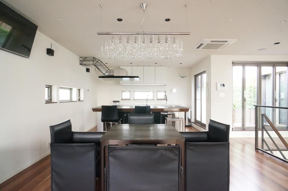 Immagine di una sala da pranzo aperta verso la cucina contemporanea con pareti bianche e parquet scuro