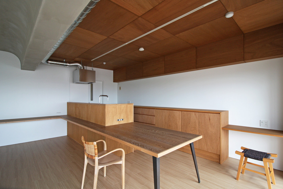 Foto di una sala da pranzo aperta verso il soggiorno moderna con pareti bianche, pavimento in compensato e pavimento marrone