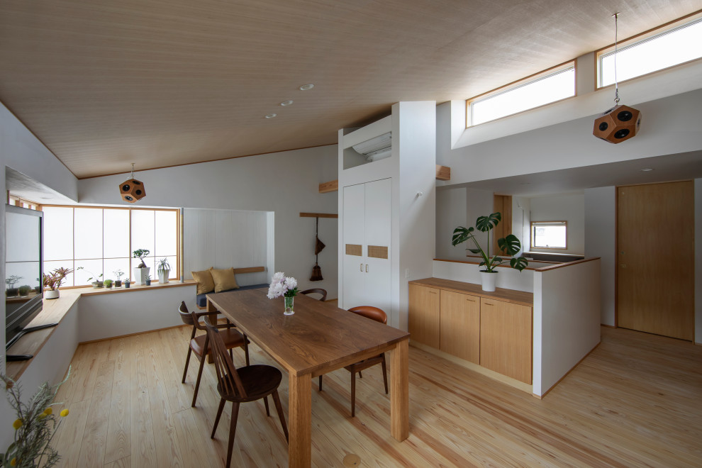 Diseño de comedor abovedado contemporáneo abierto con paredes blancas, suelo de madera clara, suelo beige y madera