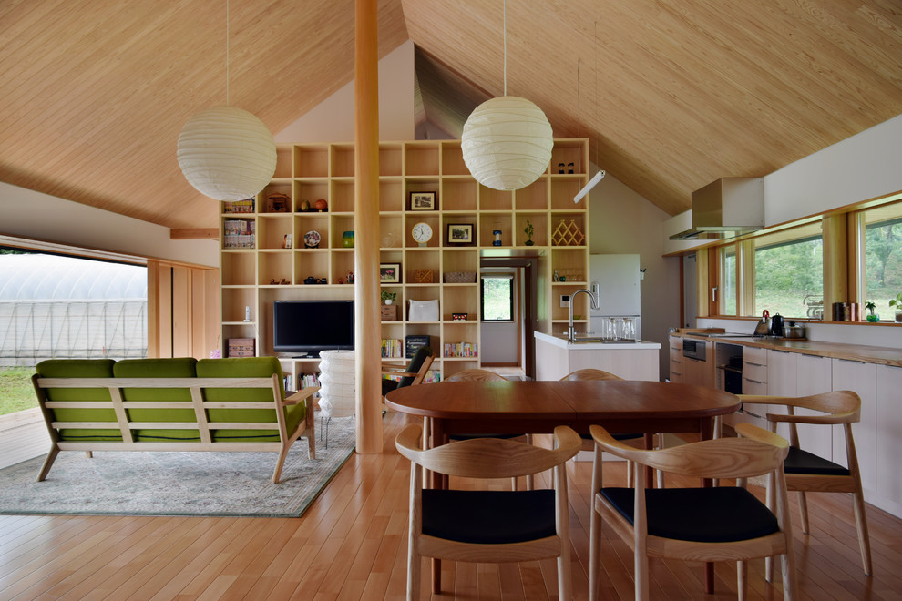 Réalisation d'une salle à manger ouverte sur le salon asiatique avec un sol en bois brun, aucune cheminée et un mur beige.