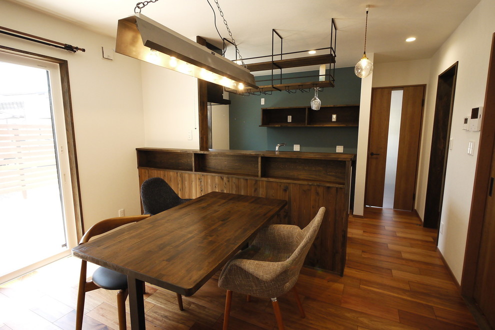 Immagine di una sala da pranzo aperta verso il soggiorno etnica con pareti multicolore, pavimento in compensato, nessun camino e pavimento marrone
