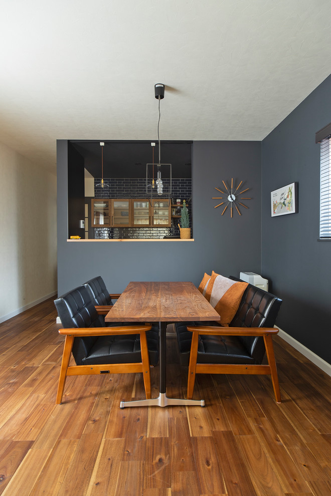 Ejemplo de comedor actual de tamaño medio abierto con paredes negras y suelo de madera en tonos medios