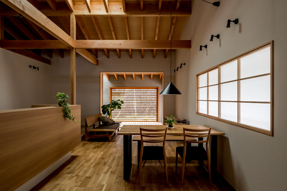 Foto di una sala da pranzo aperta verso il soggiorno etnica con pareti grigie, pavimento in legno massello medio e pavimento marrone
