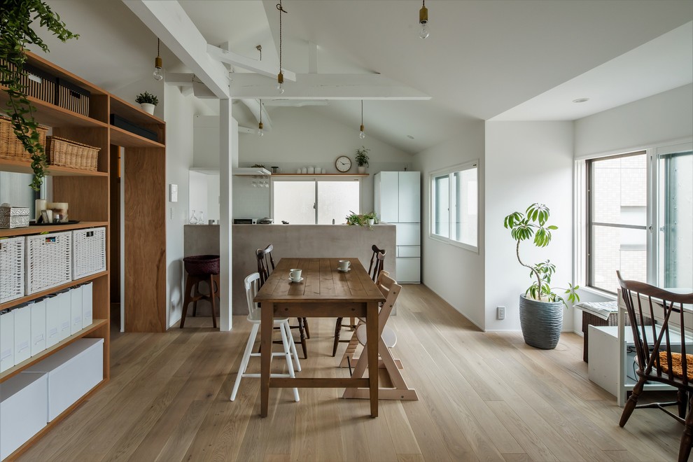 Cette image montre une petite salle à manger ouverte sur le salon design avec un mur blanc, parquet clair, aucune cheminée et un sol blanc.