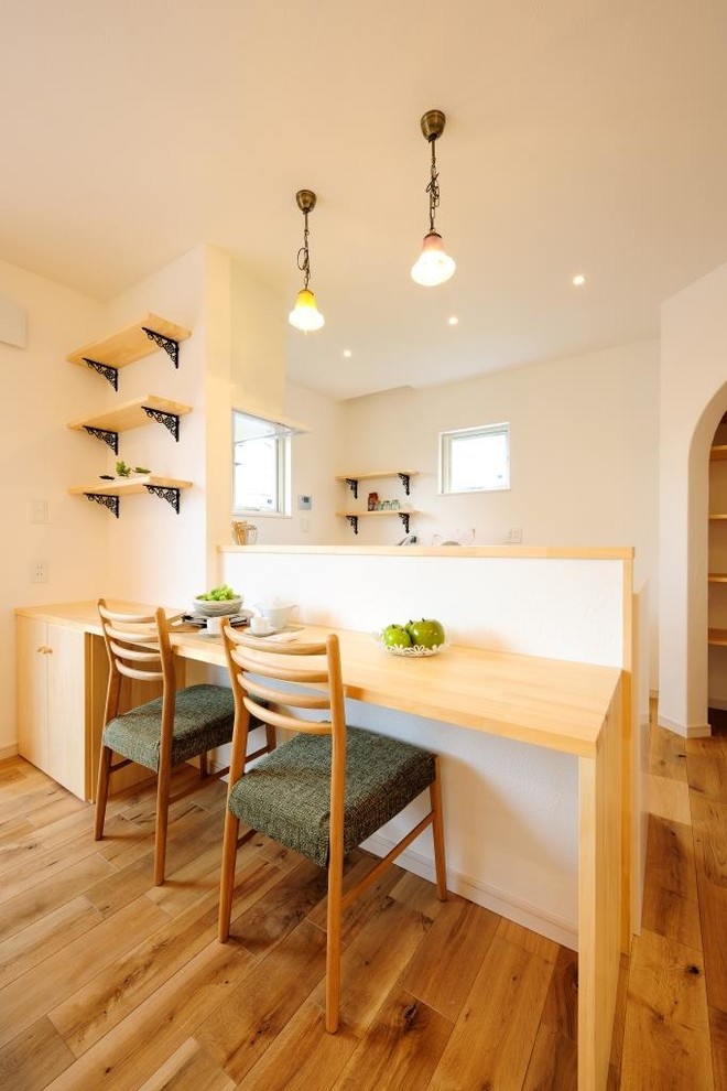 Cette photo montre une salle à manger ouverte sur le salon asiatique avec un mur blanc, un sol en bois brun, aucune cheminée et un sol marron.