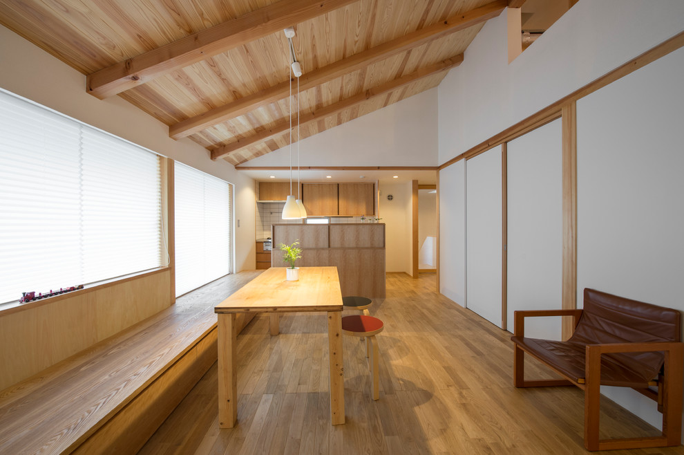 Esempio di una sala da pranzo aperta verso il soggiorno etnica con pareti bianche, pavimento in legno massello medio e pavimento marrone