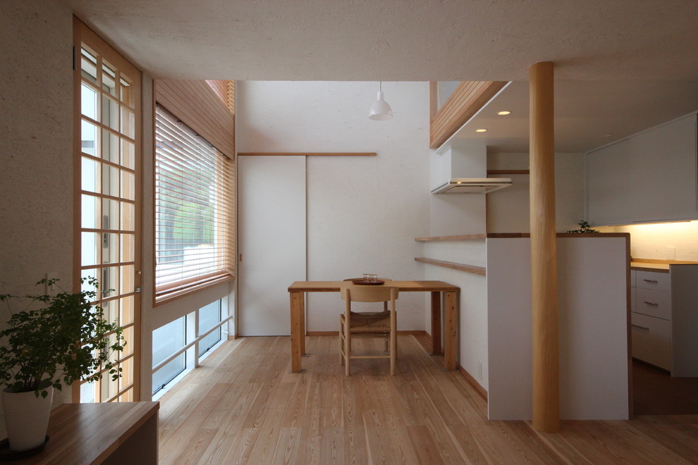 На фото: столовая в восточном стиле с белыми стенами, светлым паркетным полом и коричневым полом с