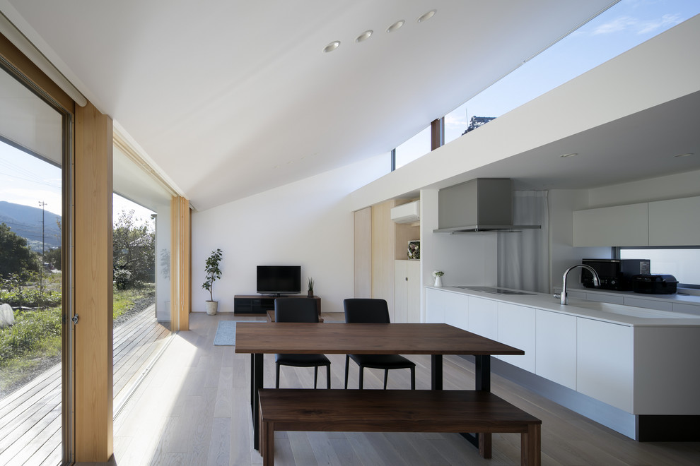 Idee per una sala da pranzo aperta verso il soggiorno minimalista con pareti bianche, pavimento in legno verniciato e pavimento beige
