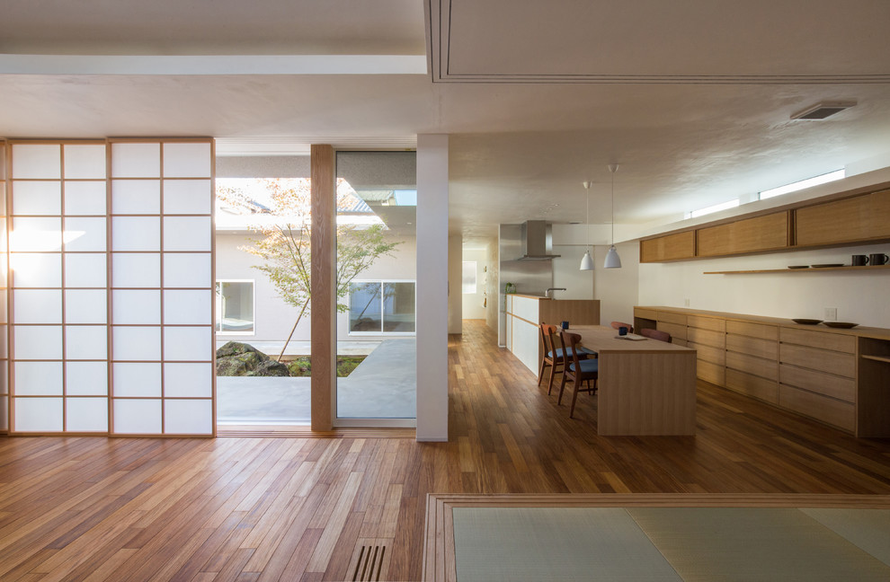 Offenes Asiatisches Esszimmer mit weißer Wandfarbe, braunem Holzboden und braunem Boden in Nagoya