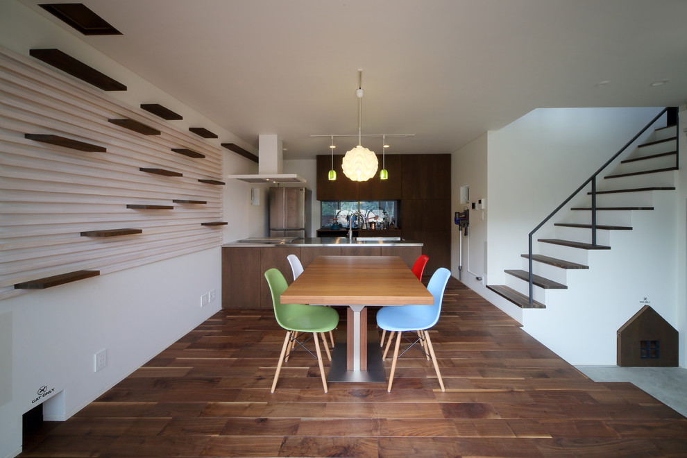 Réalisation d'une salle à manger ouverte sur le salon minimaliste de taille moyenne avec un mur blanc, parquet foncé et un sol marron.