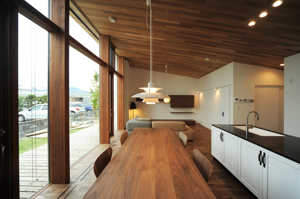 Foto di una sala da pranzo aperta verso il soggiorno etnica con pareti beige, pavimento in legno massello medio e pavimento marrone