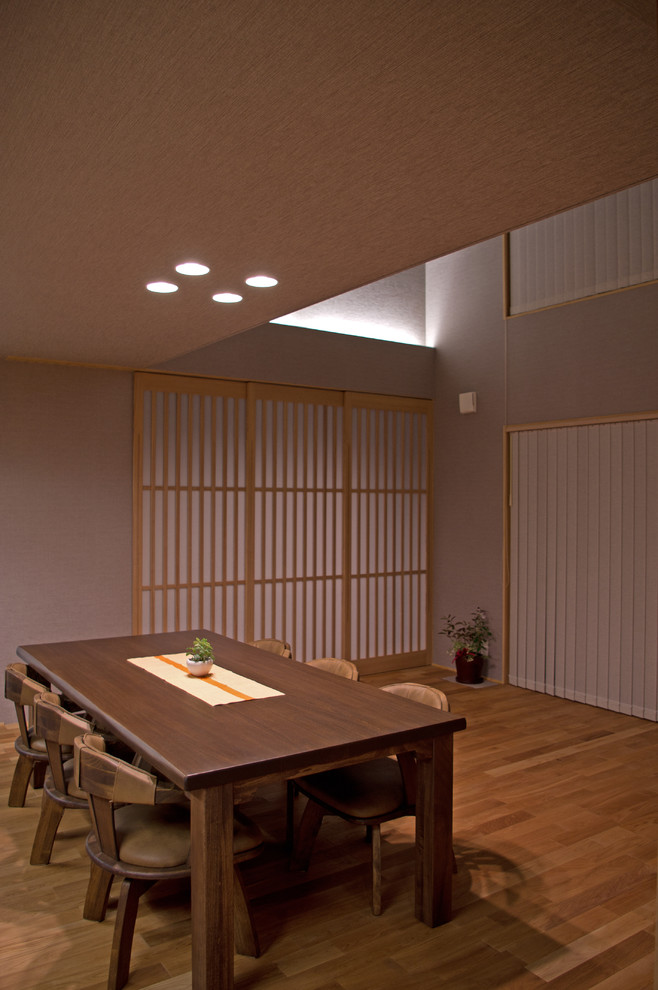 Cette image montre une salle à manger asiatique avec un mur gris, un sol en bois brun, un sol marron et éclairage.